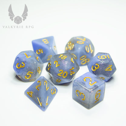 Valkyrie RPG | Online Dice Store UK | Niflheim Vela - Plumes of opaque blue-grey, flowing and coiling between voids of subtle grey resin infused with fine purple hued glitters; all finished with gold inking. 